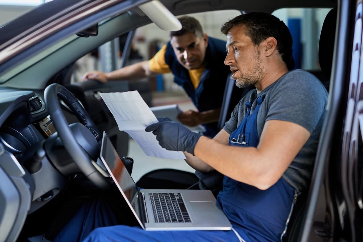 Inspector reviewing an inspection report on a laptop inside a vehicle
