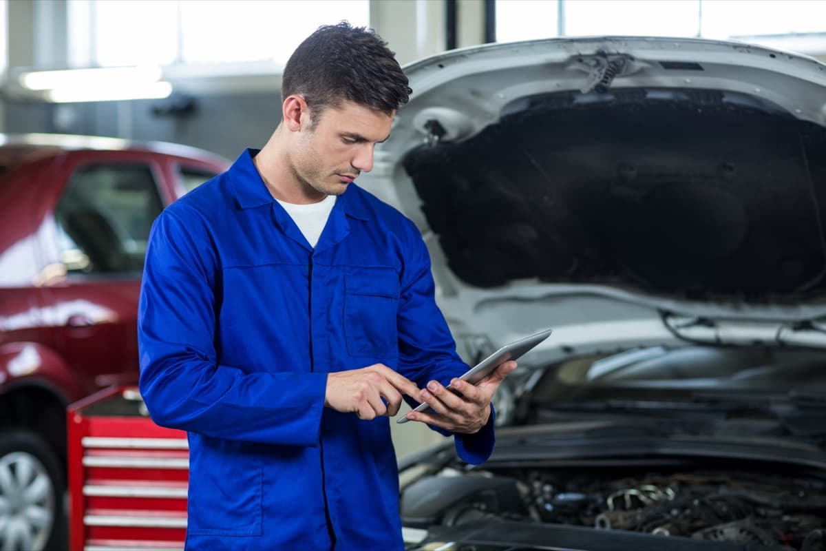 Technician inspecting an engine bay with a tablet